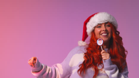 Studio-Shot-Of-Young-Gen-Z-Woman-Wearing-Christmas-Santa-Hat-Dancing-Against-Pink-Background-At-Party
